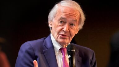 Senator Ed Markey holds a microphone while he speaks at an event.