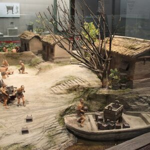 photo of a diaorama showing a Bronze Age cillage, with people pulling something on a sledge toward a boat