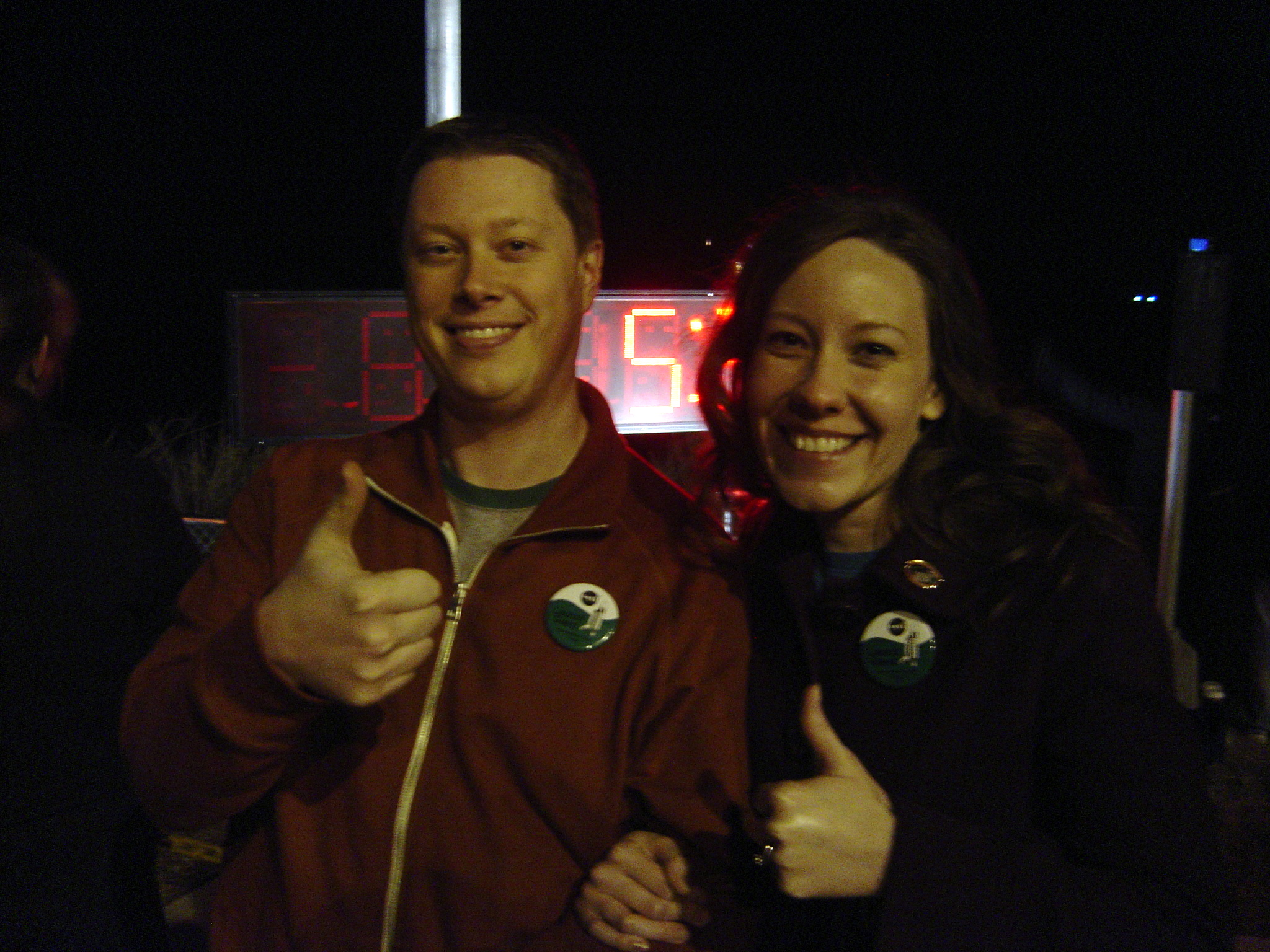 Photograph of two tired people giving a thumbs-up to the camera