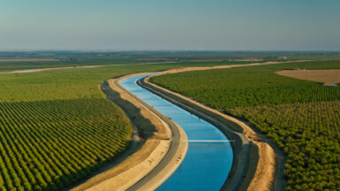 Aerial shot of farmland and aqueduct just off interstate 5 in Stanislaus County, California on a sunny afternoon in autumn.