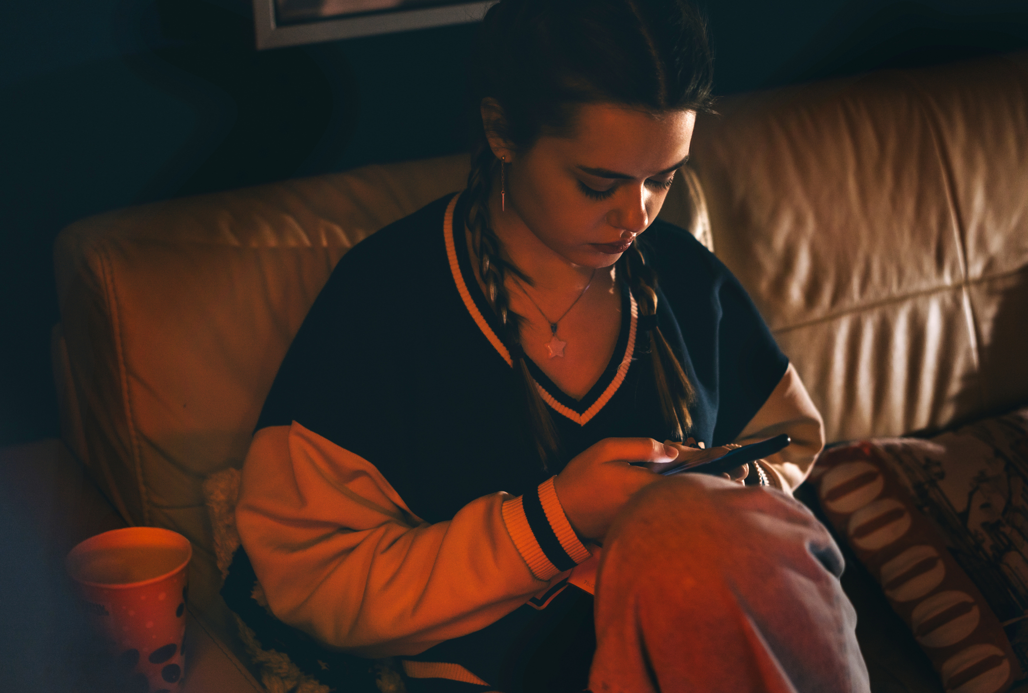 A smartphone image illustrates a school deepfake case involving AI-generated sexualized images of students.