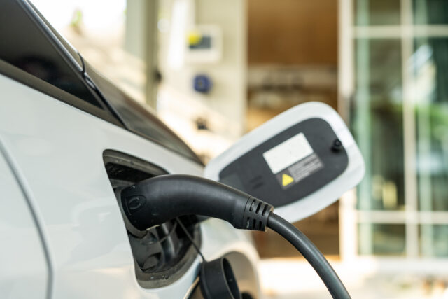 Electric car connected to a charging station, emphasizing modern technology and eco-friendly transportation. Close-up shot in an urban environment with a focus on sustainability and clean energy for a green future.