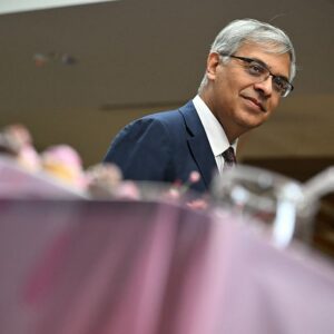 Image of a pink tablecloth with a man in a suit standing behind the table.