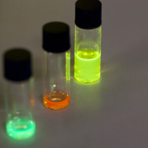 Three small jars that have (left to right) teal, red, and green-colored quantum dots