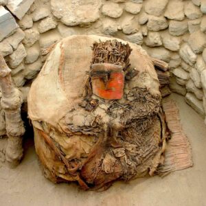 photo of a funerary bundle with a red-painted mask adorned with feathers