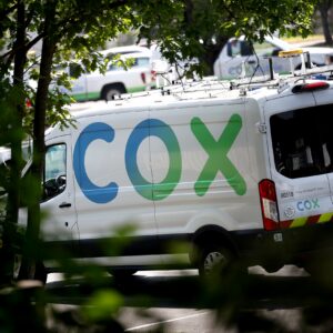 A cable service van with a large Cox logo painted on its side.