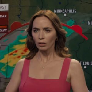 woman in a red dress standing in front of a weather looking confused