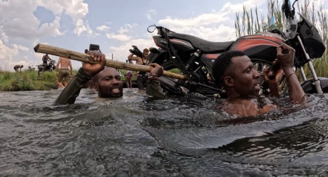Luchazi tribal hunters carry a motorcycle across a river near the Angolan Highlands