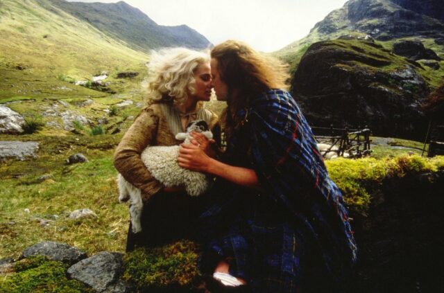 woman with great hair holding a lamb touching heads with a younger looking Scotsman