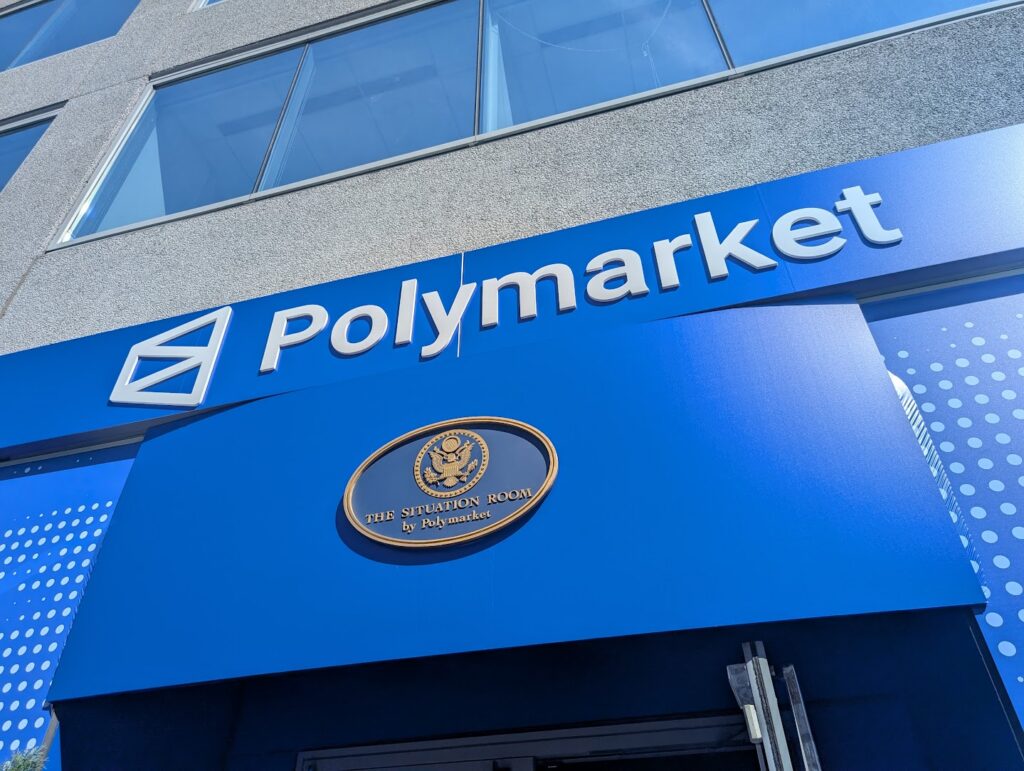Image of the facade of a building with a blue awning and a Polymarket logo.