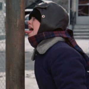young boy in winter gear, hat and scarf with his tongue sticking out and frozen to a metal pole