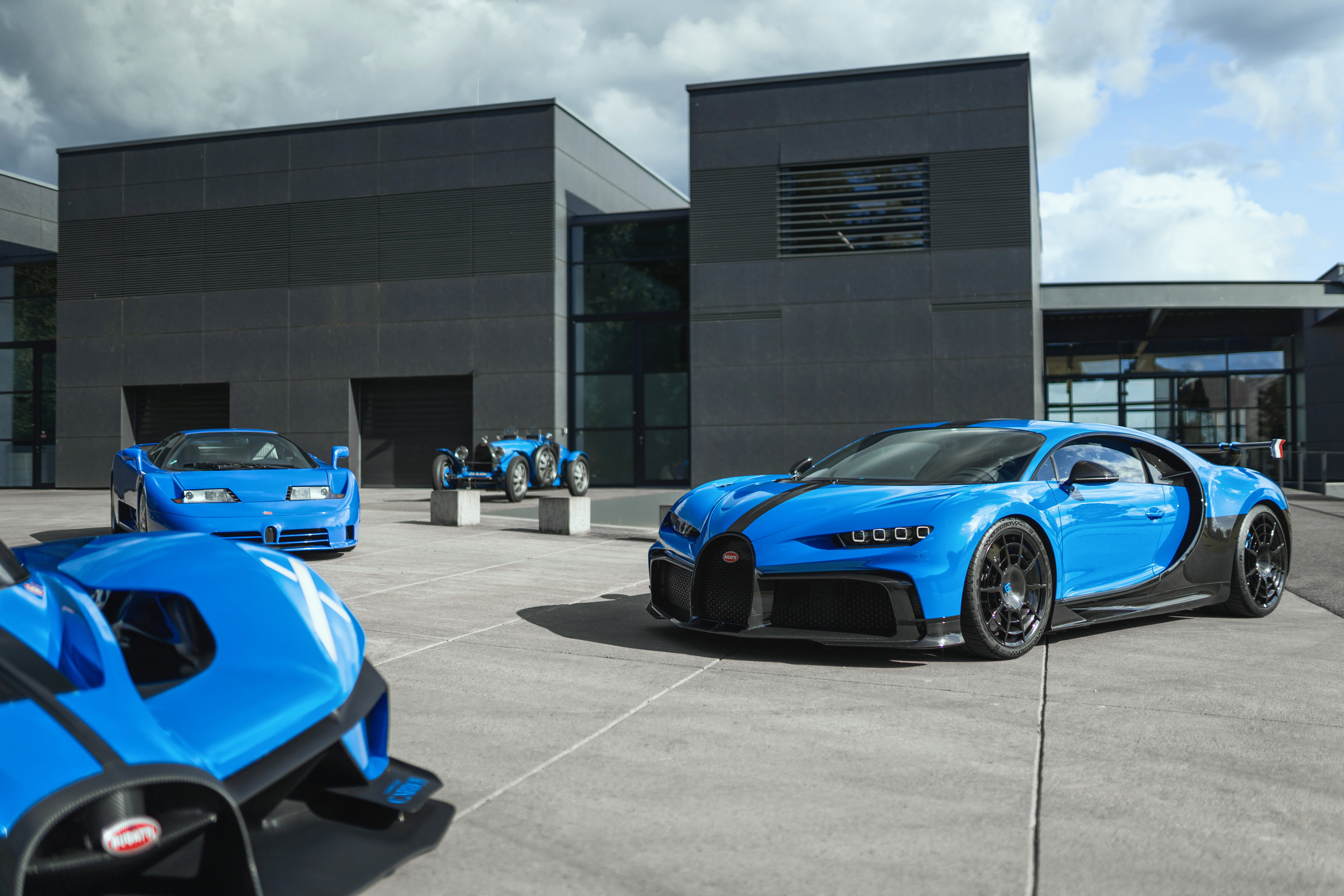 A Bugatti Chiron, EB110, Type-35, and the corner of another one are parked together.