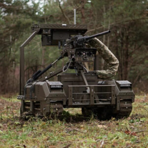A Droid TW 12.7 military robot with tracks and armed with a remote-controlled machine gun is seen sitting in a forested area.