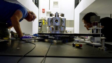 NIST scientists Stephan Schlamminger (left) and Vincent Lee examine the torsion balance they used to measure the gravitational constant, big G, a decade-long undertaking.