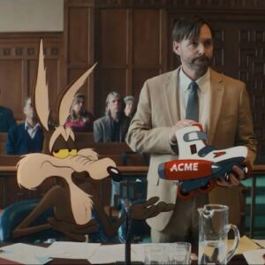 animated Wile E. Coyote seated in a courtroom while his lawyer holds up an Acme product