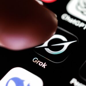 A person's finger hovering over the Grok app icon on a phone screen.