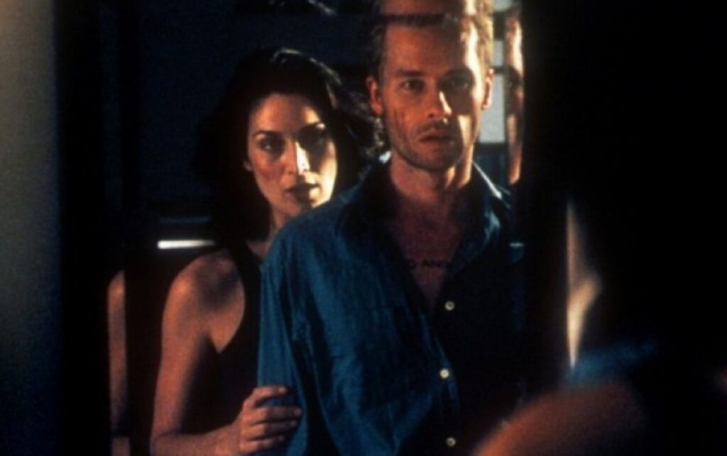 man with woman standing just behind him, both reflected in the mirror