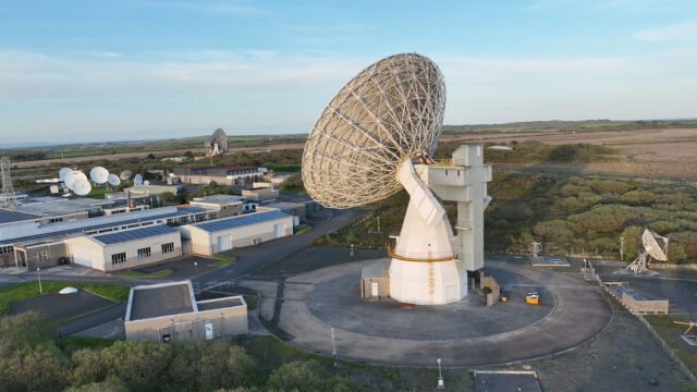 a large radio dish antenna stands near a number of buildings