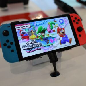 A Nintendo Switch handheld gaming console at a store with a demo of Super Mario Bros. Wonder displayed on the screen.