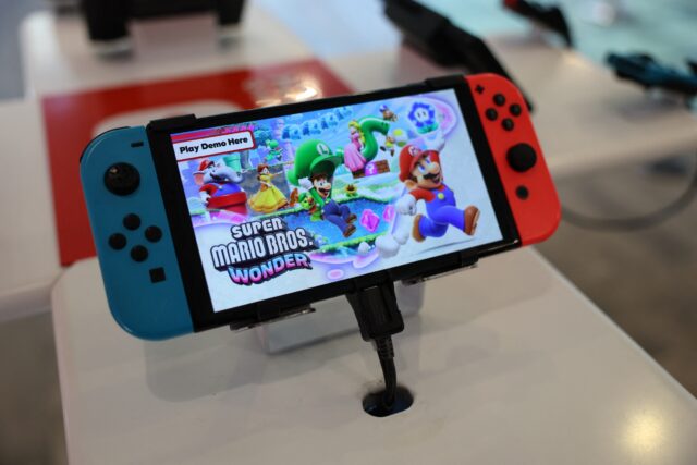 A Nintendo Switch handheld gaming console at a store with a demo of Super Mario Bros. Wonder displayed on the screen.