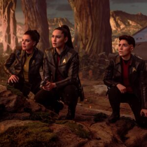 Enterprise crew members on an alien planet hunched down and surveying the terrain