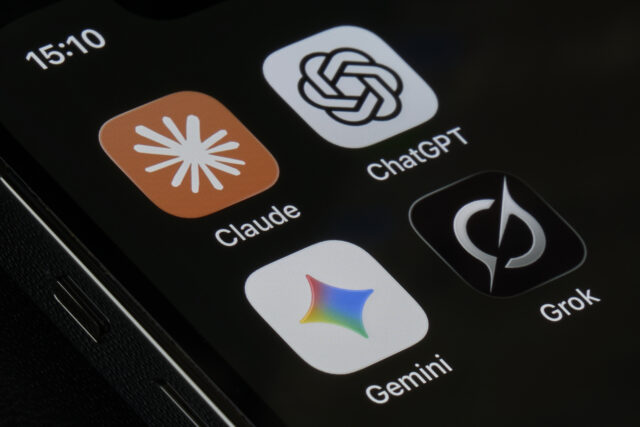 An iPhone screen photographed at close range displays four AI assistant application icons, including Claude by Anthropic, ChatGPT by OpenAI, Gemini by Google, and Grok by xAI.