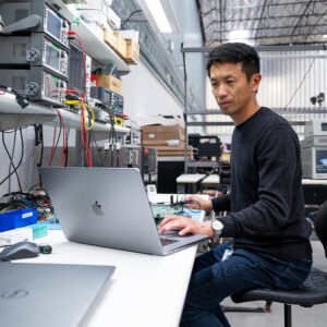 A man sits at a lab bench with a laptop