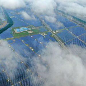 Aerial view of a solar power plant that's partly obscured by low-lying clouds.