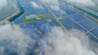 Aerial view of a solar power plant that's partly obscured by low-lying clouds.