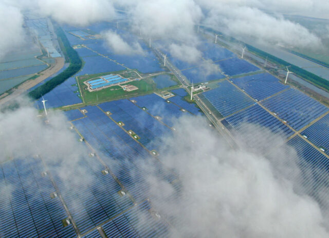 Aerial view of a solar power plant that's partly obscured by low-lying clouds.