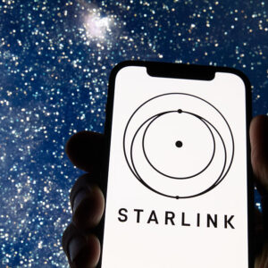 The Starlink logo appears on a smartphone screen with a starry night sky in the background.