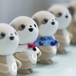 Four plastic anthropomorphic toy dogs are lined up on display at a trade show.
