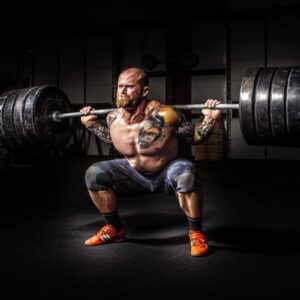 A man performing a squat with a barbell loaded with four weight plates on each end