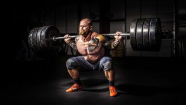 A man performing a squat with a barbell loaded with four weight plates on each end