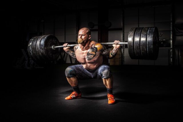 Olympic weightlifter performing snatch with barbell flexing