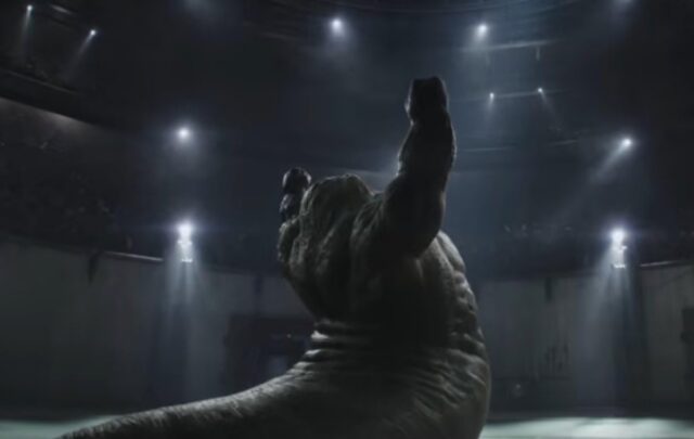 large muscled worm creature raising arms in a sign of victory in a combat ring