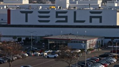 Aerial view of a Tesla factory showing the parking lot and exterior