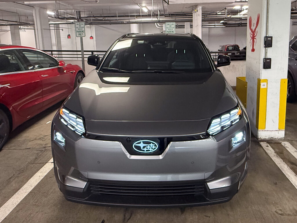 A Subaru Solterra parked underground, its Subaru logo is illuminated.