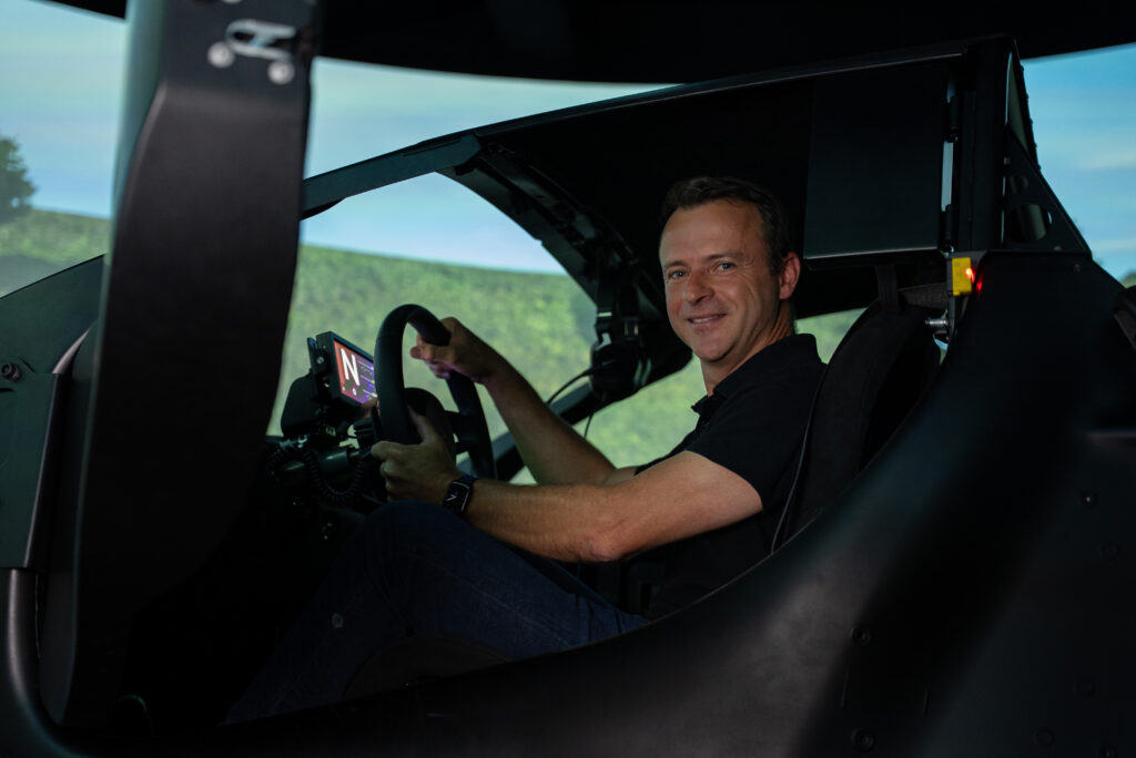 A man sits in the cockpit of a driving sim
