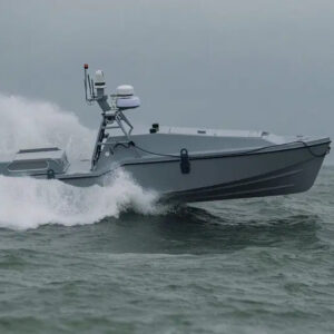 An image of the Corsair autonomous surface vessel developed by Saronic Technologies racing across the surface of a blue-gray ocean with white water foam in its wake.