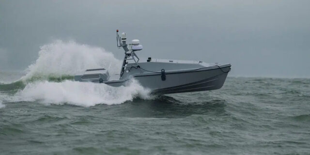 An image of the Corsair autonomous surface vessel developed by Saronic Technologies racing across the surface of a blue-gray ocean with white water foam in its wake.