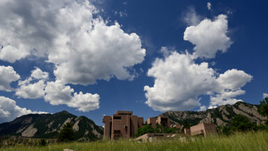 The National Center for Atmospheric Research Mesa Lab seen at a distance beneath a sky full of clouds.