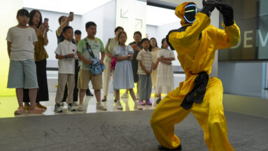 Children watch a martial arts performance by Unitree robots at a humanoid robot store on June 1, 2026 in Zhengzhou, Henan Province of China. The robot is wearing yellow martial arts clothing.