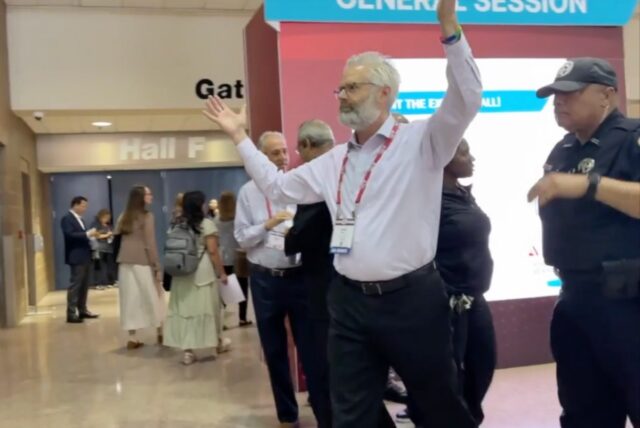 Police escort Dr. Steven Kahn out of a medical conference in New Orleans for handling out copies