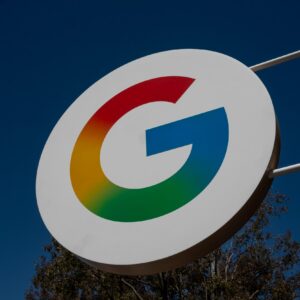 A large sign with Google's "G" logo hangs outside during the daytime.