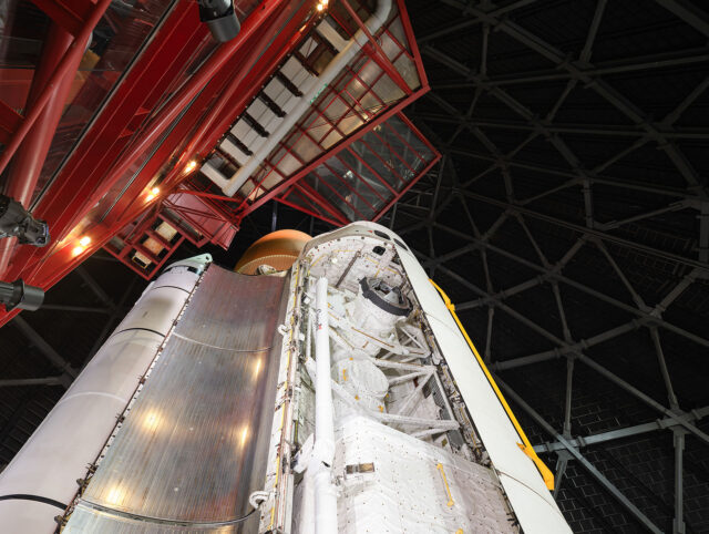 the indoor vertical exhibit of a space shuttle stack includes an open payload bay showing the equipment inside the cargo hold
