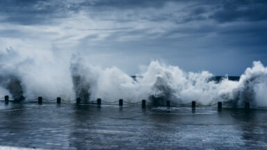 Waves crash into a sea wall at the edge of the ocean.
