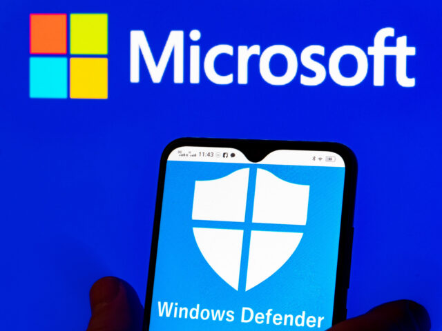 In this photo illustration, the Microsoft Windows Defender logo is seen displayed on a smartphone and Microsoft logo in
