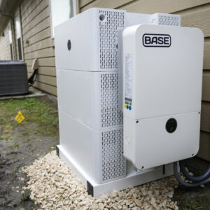 A white-colored residential battery with the name "BASE" on the side sits on the side of a brown-colored house in Houston, Texas.