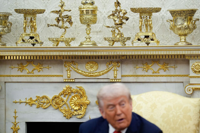 Tổng thống Trump ngồi trước bức tường trang trí bằng lá vàng